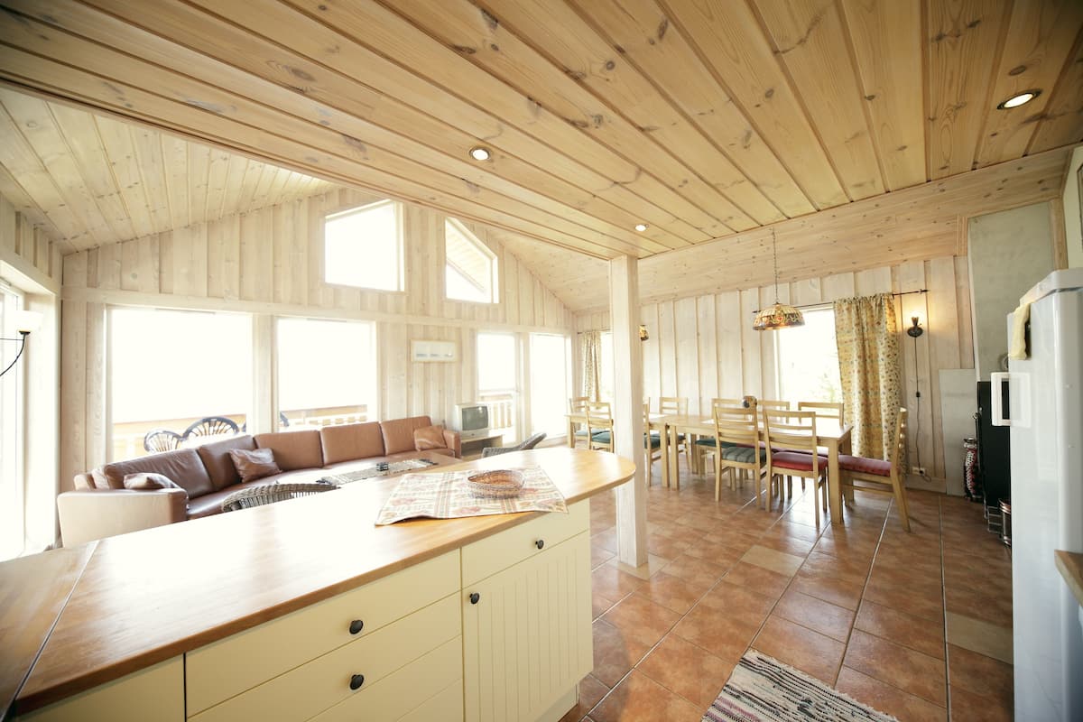 A spacious kitchen with wooden cabinets, a large island, and a dining area with wooden chairs and a table.