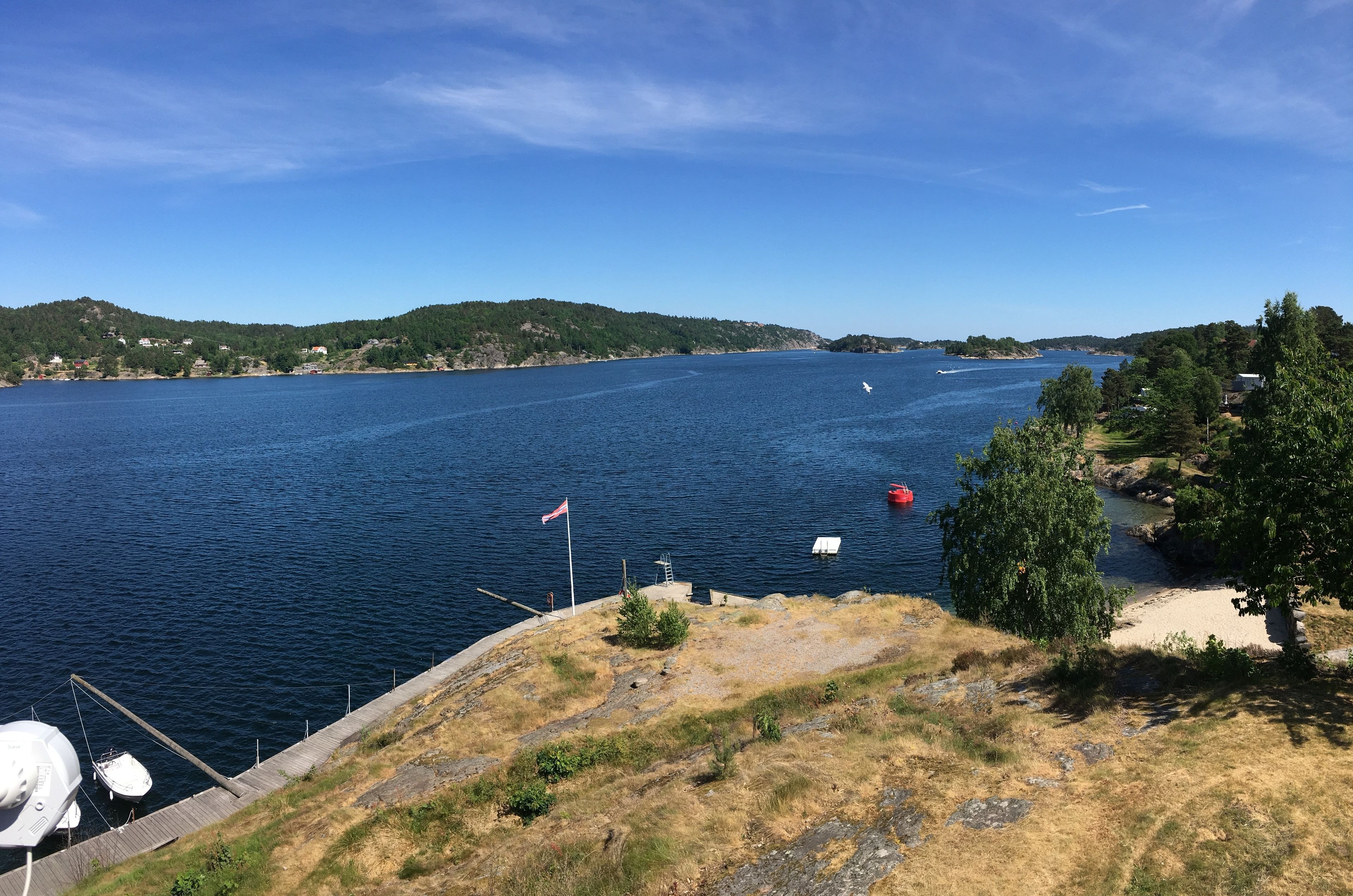 A coastal view with a dock, boats, and a flag.
