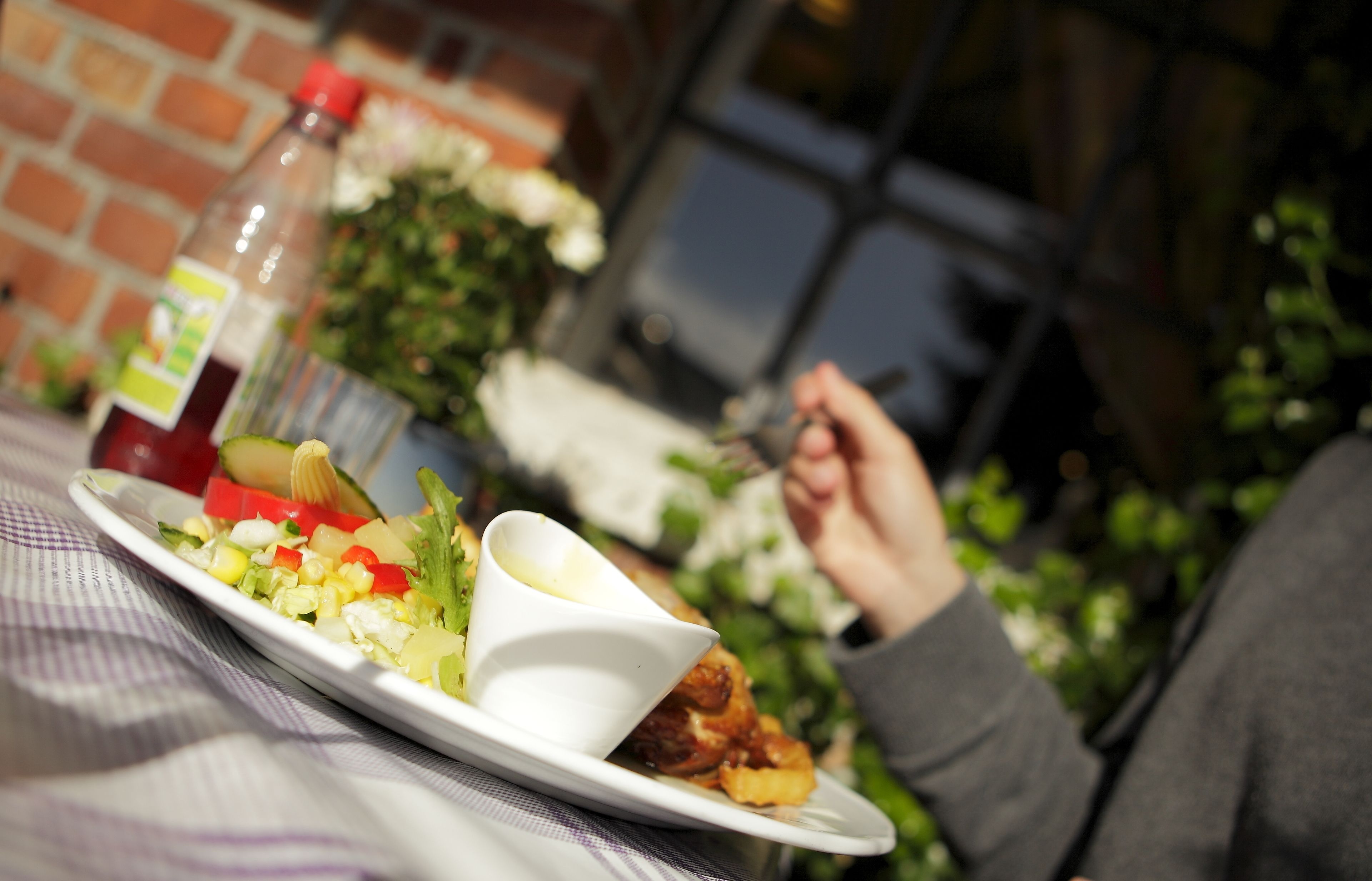 A dining table with a plate of food, a bottle of sauce, and a cup of sauce.