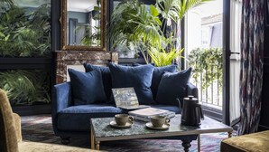 Ein gemütliches Wohnzimmer mit einem blauen Sofa, einem Couchtisch mit Tassen und einem Buch sowie einem großen Spiegel.