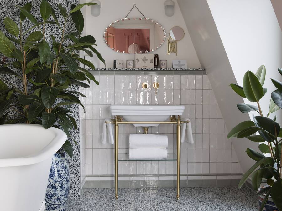 A bathroom with a freestanding bathtub, a white sink with gold fixtures, and a tiled backsplash.