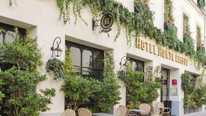 Ein Hotelgebäude mit Außenbereich, Sitzgelegenheiten, Efeu bewachsenen Wänden und einem Schild mit der Aufschrift 'HOTEL MONTE CHISTO'.