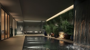 A modern indoor pool area with a seating area, plants, and a patterned wall.