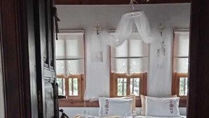 Una habitación tradicional con cama, suelo de madera y un ventanal grande.