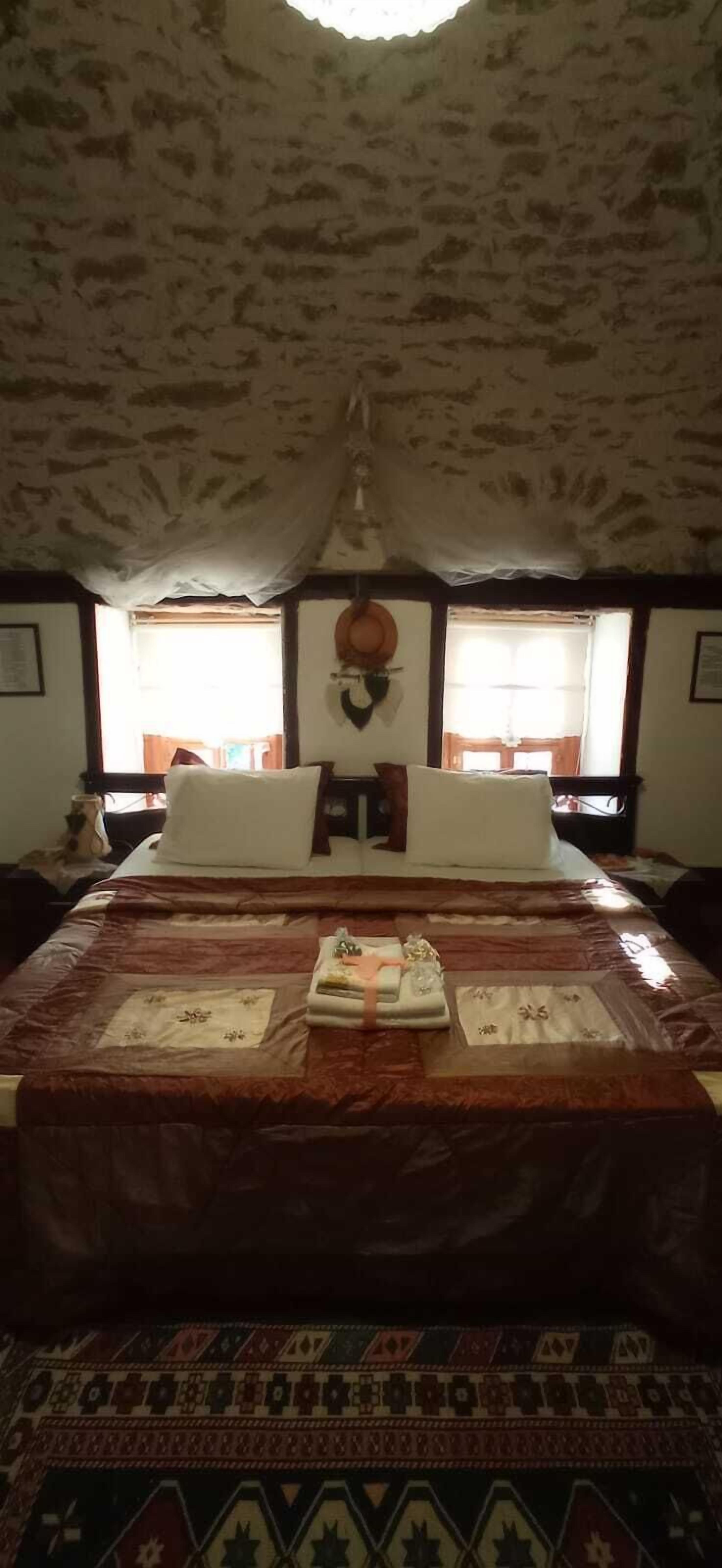 A bedroom with a large bed, a patterned rug, and a rustic ceiling.