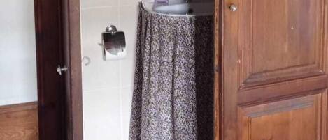 A bathroom with a wooden door, a mirror, a towel rack, and a toilet paper holder.