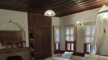 Una habitación rústica con techos y paredes de madera, dos camas con sábanas blancas, un aparador de madera y un espejo con marco decorativo.