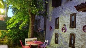Un espacio al aire libre rústico con mesa y sillas, un banco y un árbol que da sombra.