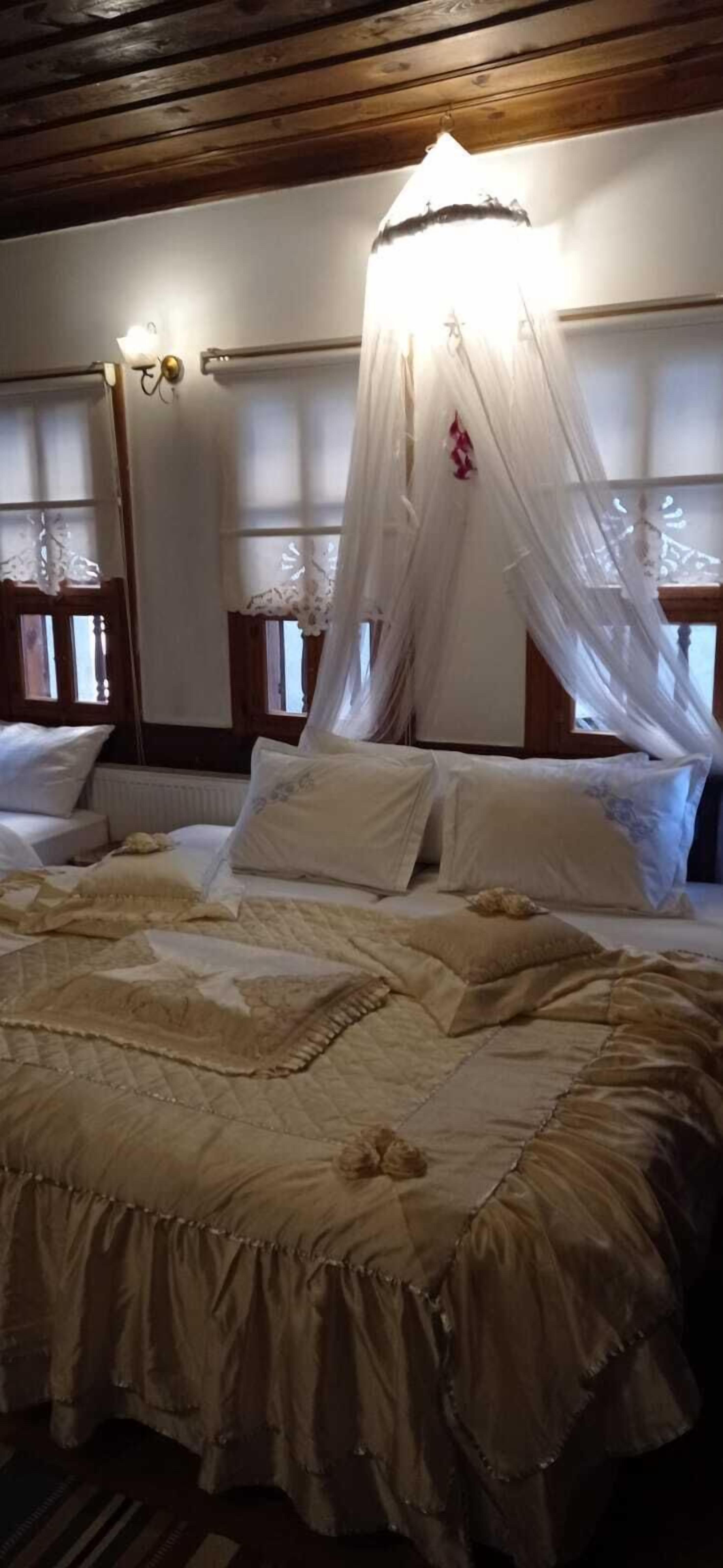 Uma cama com dossel, uma mesa de cabeceira e um abajur fixado na parede.