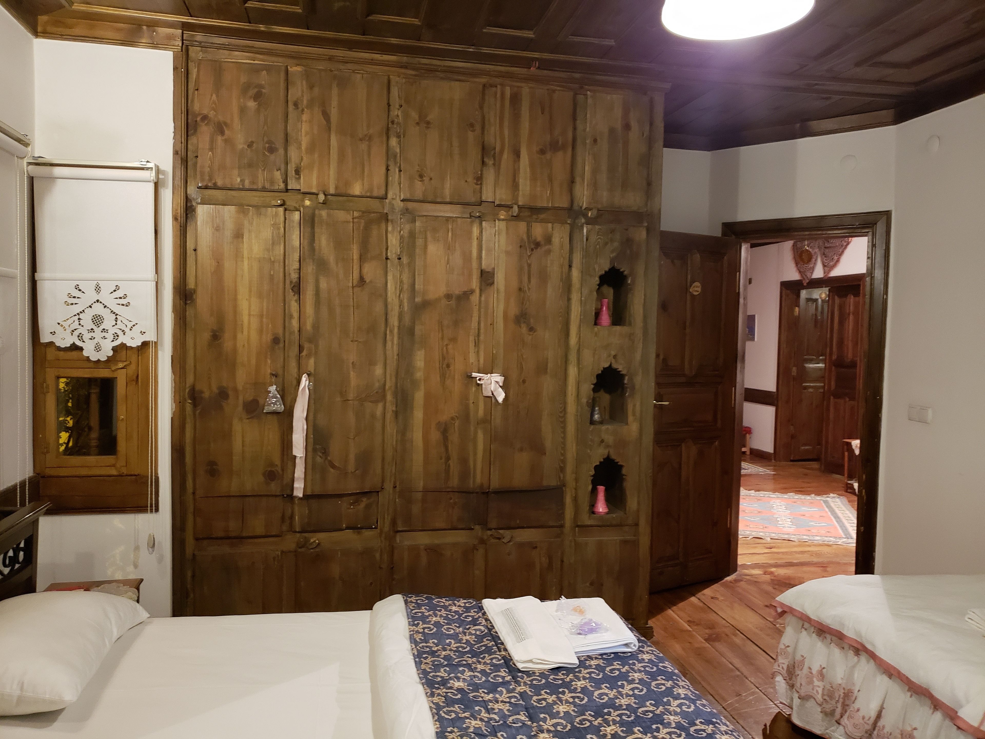 Ein Zimmer mit zwei Betten, einem Holzschrank und einem kleinen Tisch mit einem Buch.