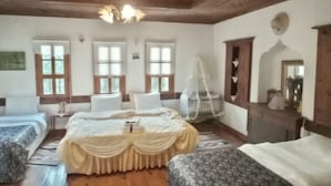 Una habitación con techo de madera, una cama con dosel blanco, suelo de madera y un tapete blanco.