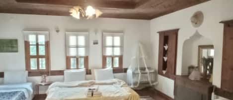 Una habitación con techo de madera, una cama con dosel blanco, suelo de madera y un tapete blanco.