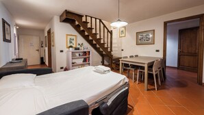 Een hotelkamer met een bed, een bureau, een stoel, een trap en een boekenplank.