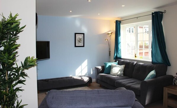 A living room with a sofa, a coffee table, a floor lamp, and a large window with curtains.