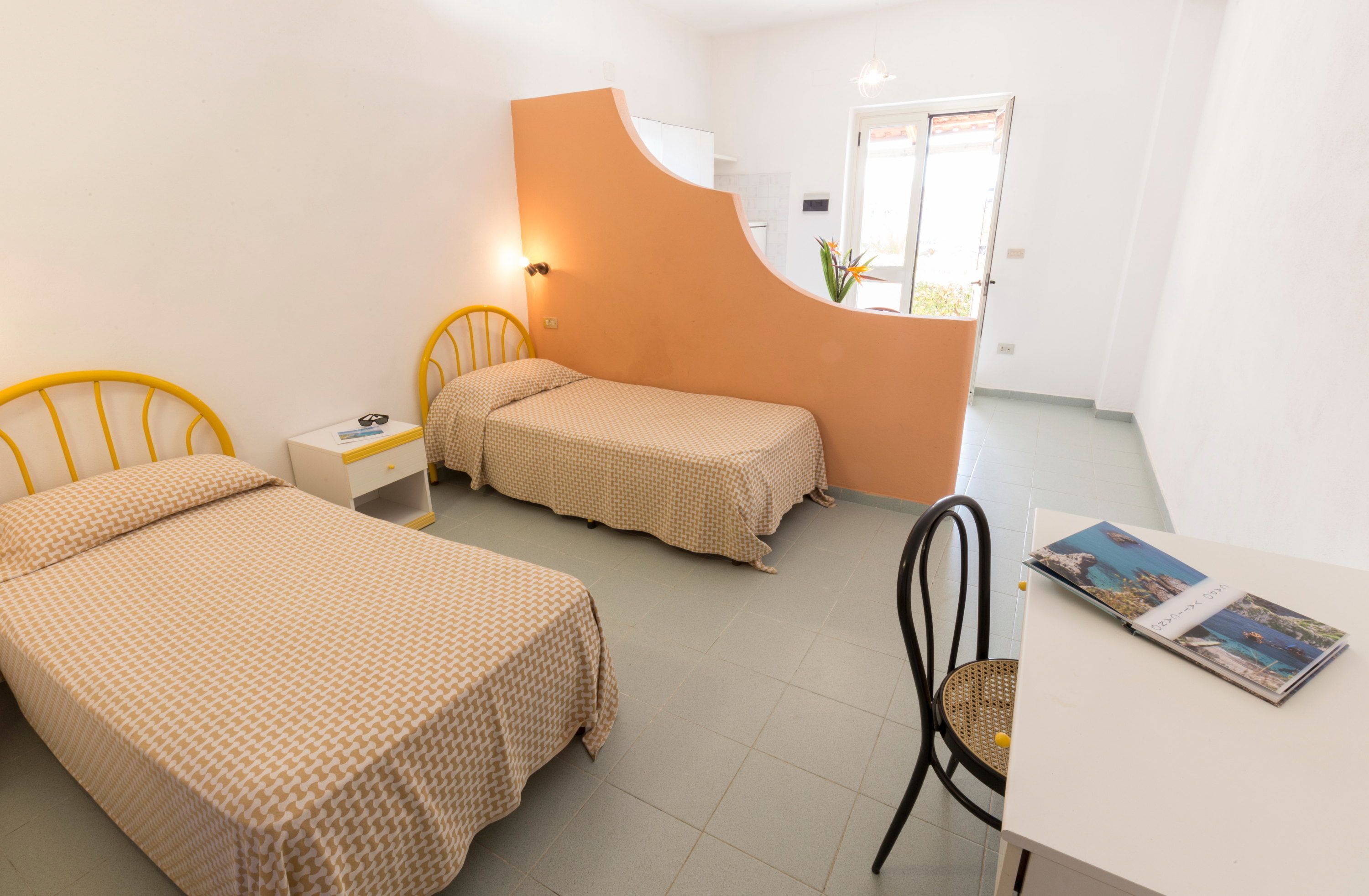 A bedroom with two beds, a desk, and a chair.