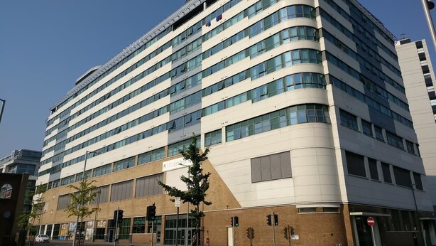 Een modern hotel met meerdere verdiepingen, een gebogen gevel, grote ramen en een duidelijke ingang met een bord.