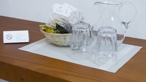 Una mesa de madera con una cesta de aperitivos, dos vasos transparentes, una jarra y un letrero con el símbolo de prohibido fumar.