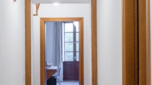 Un pasillo con puertas de madera y un escritorio con sillas, que conduce a una habitación con ventana.