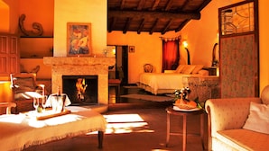 A cozy room with a fireplace, a bed, and a dining area with a table set for two. - Finca El Cabezo (Villamiel)