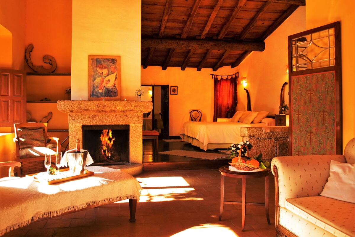 A cozy room with a fireplace, a bed, and a dining area with a table set for two.