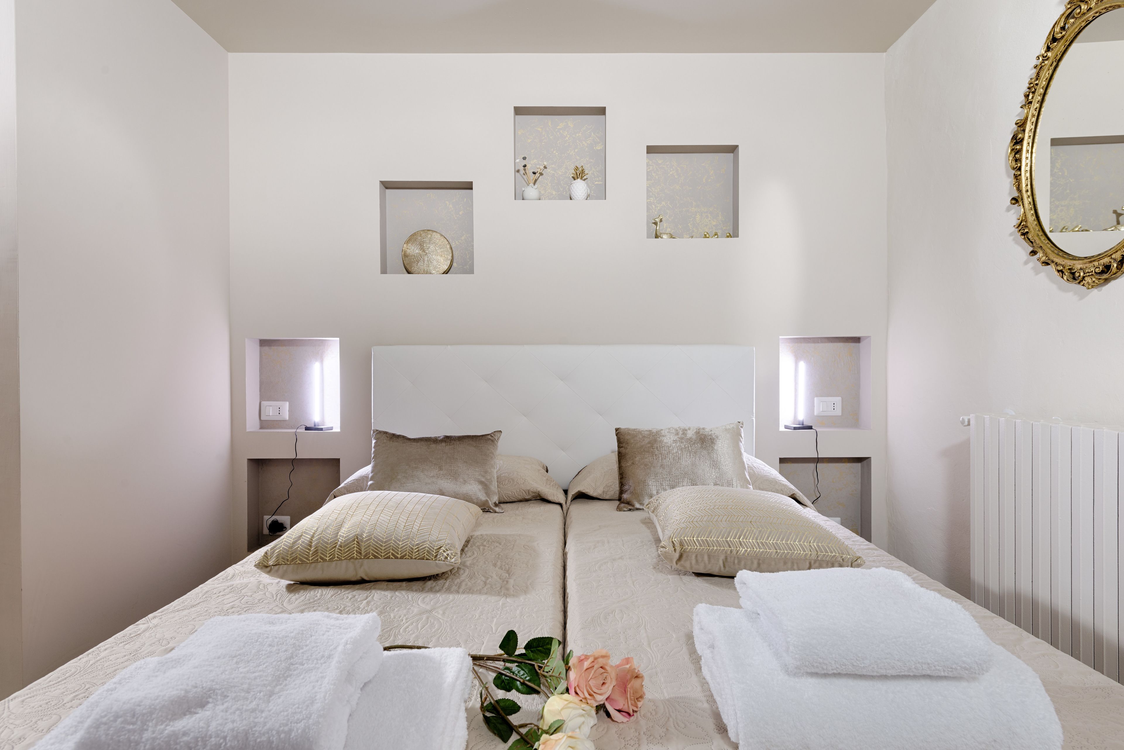 A double bed with two pillows, a bedside table with a lamp, and a wall-mounted mirror.