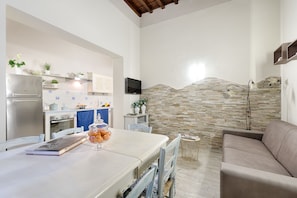 A modern kitchen with a stone backsplash, a dining area with a table and chairs, and a living area with a sofa. - Santa Croce Cathedral by Mmega (Florence)