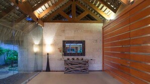 A spa room with a stone wall, wooden paneling, a mirror, and a log bench. - Villa Perla by Unlimted Luxury Villas (La Romana)