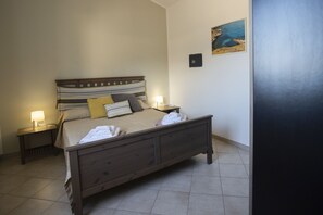 Una cama bien hecha con un cabecero a rayas, dos lámparas de noche y un cuadro en la pared.