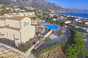 Et resort med swimmingpool, liggestole og udsigt til havet og bjergene.