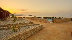 A stone-walled courtyard with a pool entrance, surrounded by plants and a view of distant mountains. - Riva Sea Apartments (Castellammare del Golfo)