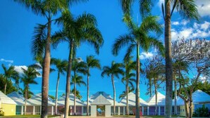 A resort with multiple white-roofed buildings, palm trees, and a clear blue sky. - Casa Feliz by Unlimited Luxury Villas (La Romana)