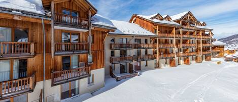 A wooden multi-story hotel with balconies and a snow-covered ground.