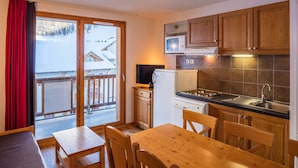 A compact kitchen with wooden cabinets, a microwave, and a refrigerator. - Noemys Les Balcons de Bois Méan (Les Orres)