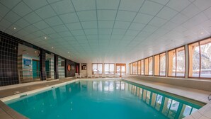 An indoor swimming pool with clear blue water, surrounded by tiled walls and large windows. - Noemys Les Balcons de Bois Méan (Les Orres)