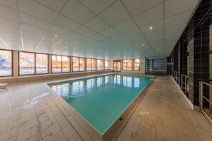 An indoor swimming pool with a tiled floor and large windows. - Noemys Les Balcons de Bois Méan (Les Orres)