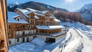 A large wooden lodge with multiple balconies and a ski slope in the background. - Noemys Les Balcons de Bois Méan (Les Orres)