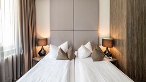 Una habitación de hotel con una cama grande, dos mesitas de noche y un cabecero.