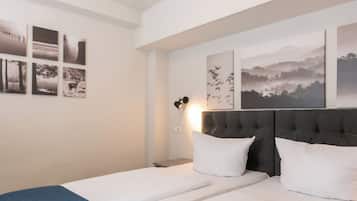 A bedroom with two beds, a headboard, and wall art.