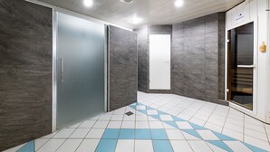 Un baño moderno con paredes grises, una puerta blanca y un suelo de baldosas con detalles azules.