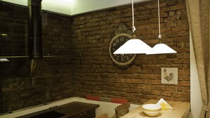 Una cocina con pared de ladrillo, un reloj y una lámpara colgante.