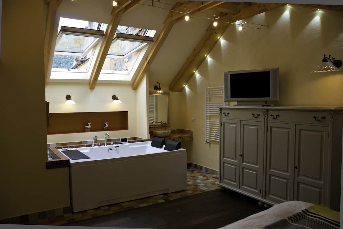 A modern bathroom with a freestanding bathtub, a vanity with a sink, and a television mounted above the cabinets.