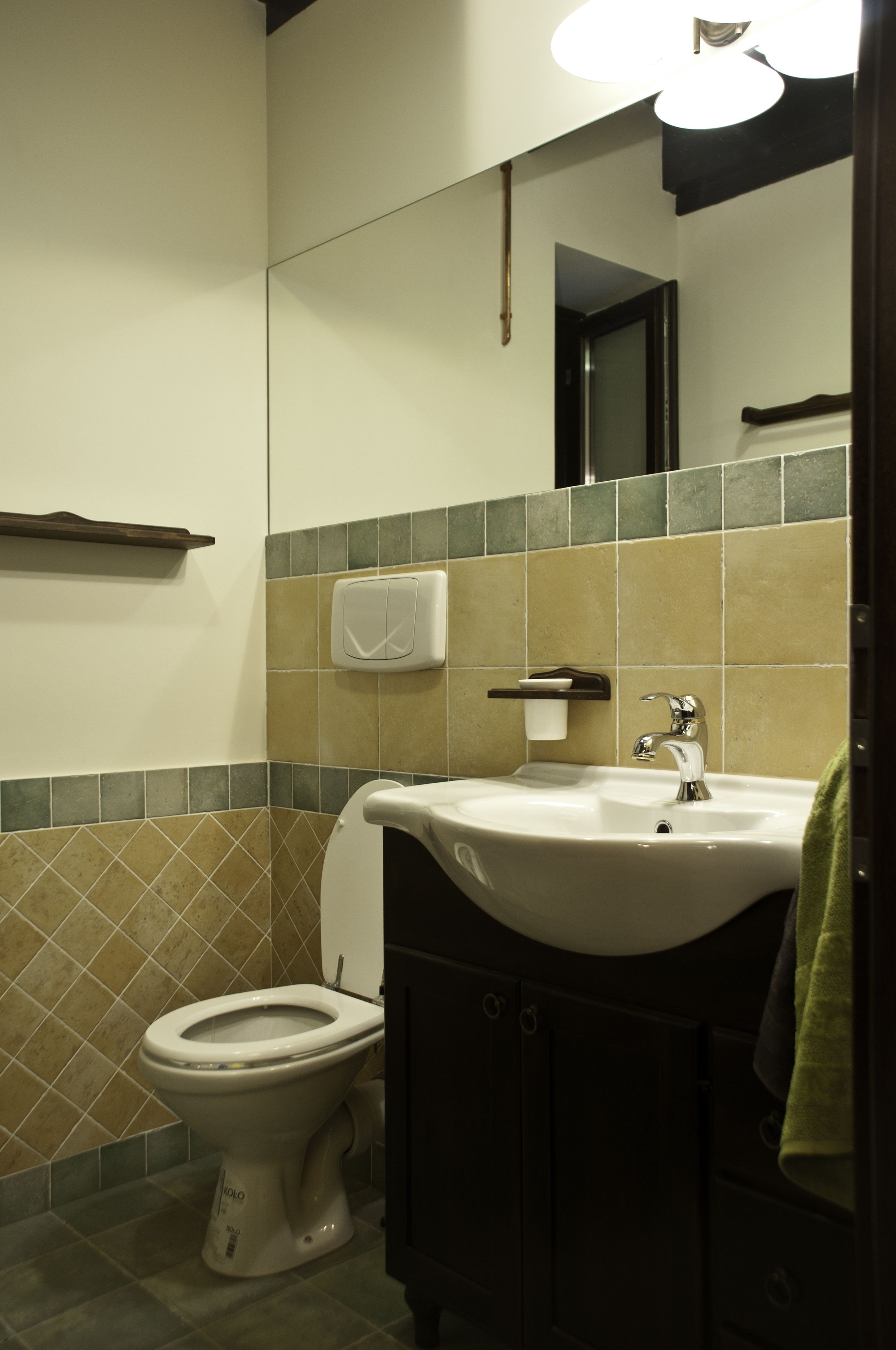 Een badkamer met toilet, wastafel en spiegel.