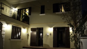 Un edificio con un patio empedrado, varias puertas y un balcón con barandillas.