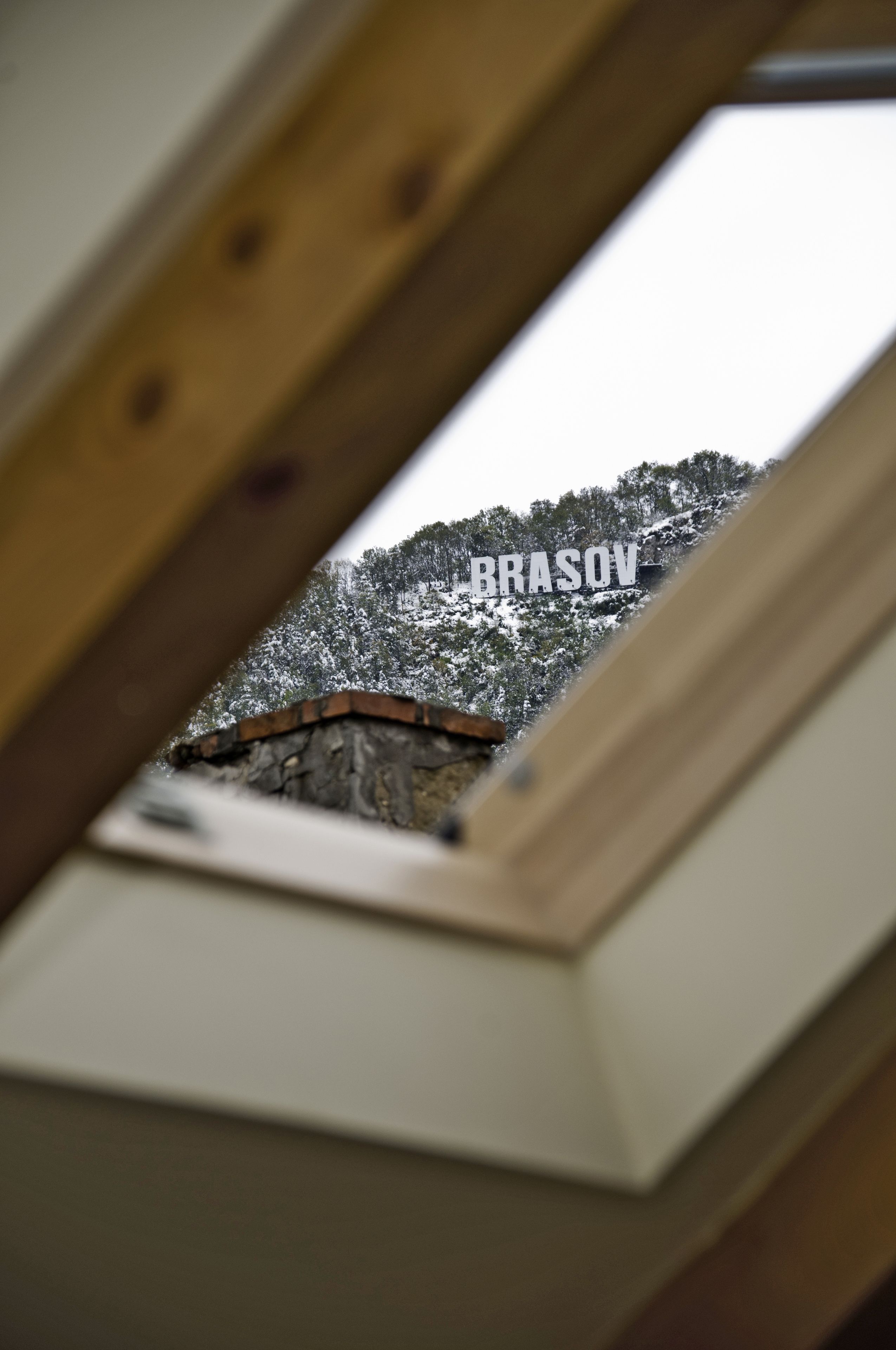 A view through a skylight of a snow-covered mountain with the text "BRASOV" visible.