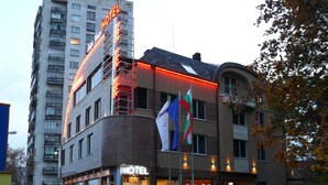 Un hôtel au design moderne, doté d’une entrée imposante et d’un mât où flotte un drapeau.