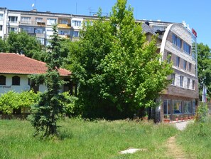 A building with a red-tiled roof, surrounded by lush greenery and a clear blue sky.