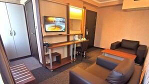 Une chambre d’hôtel équipée d ’un canapé, d’un bureau avec un ordinateur, d’une télévision et d’un mini-bar.