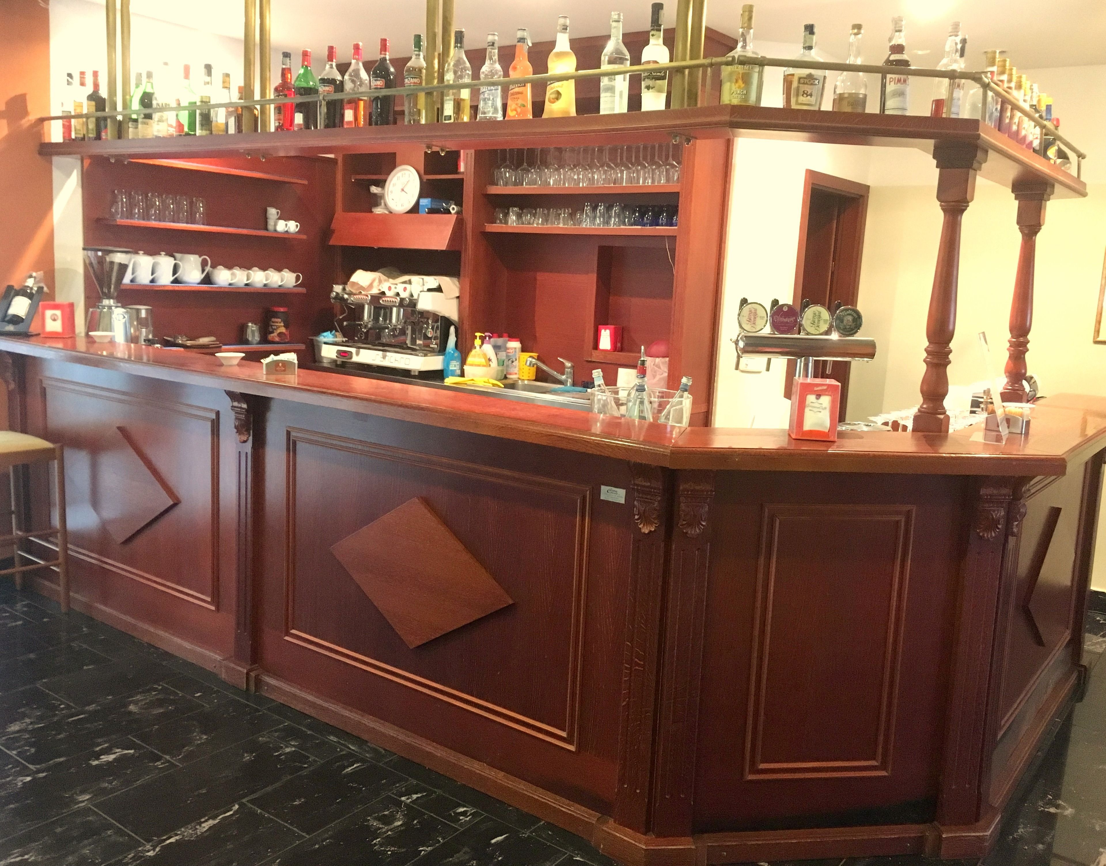 A bar area with shelves of bottles, glasses, and a coffee machine.