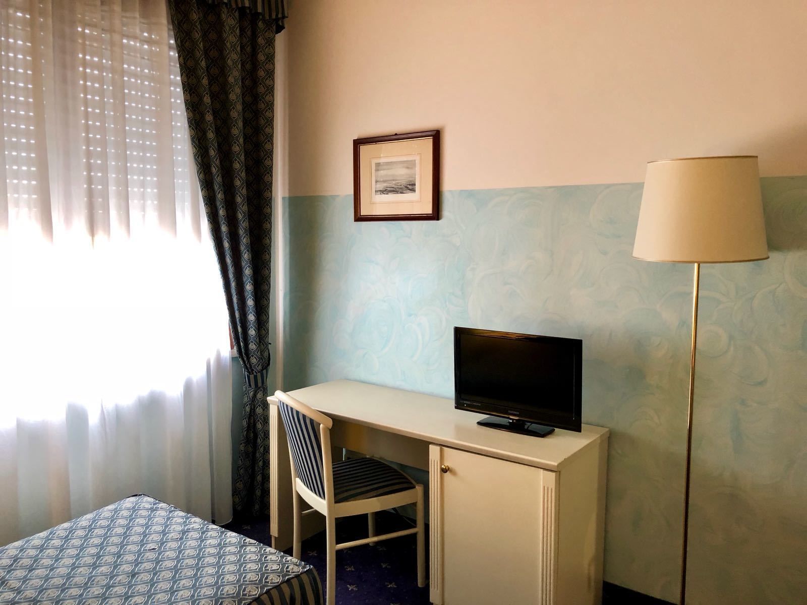 Et hotelværelse med skrivebord, stol og lampe.