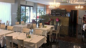 A restaurant with tables set for dining, a bar area, and a staircase leading to an upper level. - Hotel Internazionale (Gorizia)
